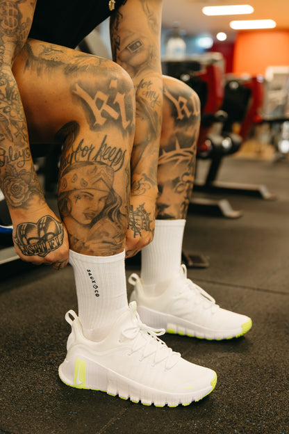 Person wearing white socks with sneakers in a gym setting